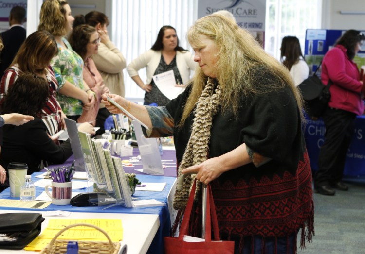Lois Dersham, who lost her job when Merrymeeting Behavioral Health Services closed, checks out employers Monday at a job fair in Brunswick. "I'd like to find a similar job, but now I worry a little about the field I'm in," she said.