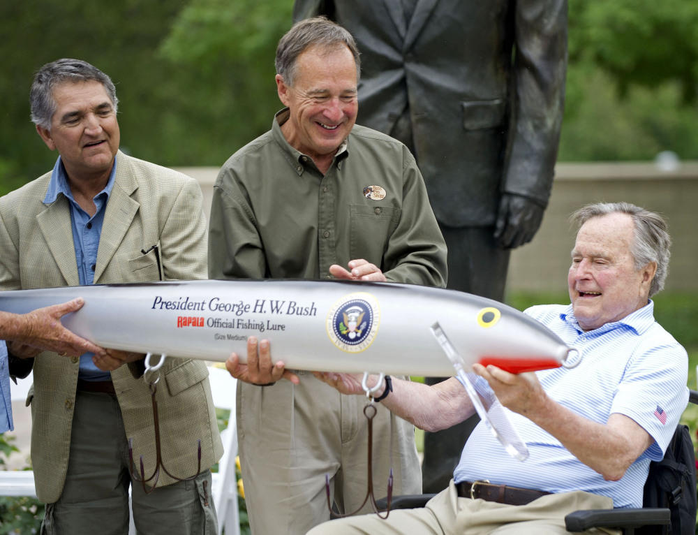 Bass Pro Shops founder Johnny Morris, center, joins Pedro Sors, president of the fishing association of the Mexican state of Tamaulipas, to present former President George H.W. Bush with a giant fishing lure Thursday at the Bush Library in College Station, Texas.