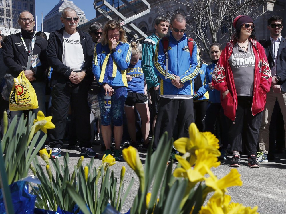 People observe a moment of silence Friday at the site where the first of two bombs detonated in 2013 at the Boston Marathon finish line on Boylston Street in Boston. Friday marked the third anniversary of the bombings, in which three died.