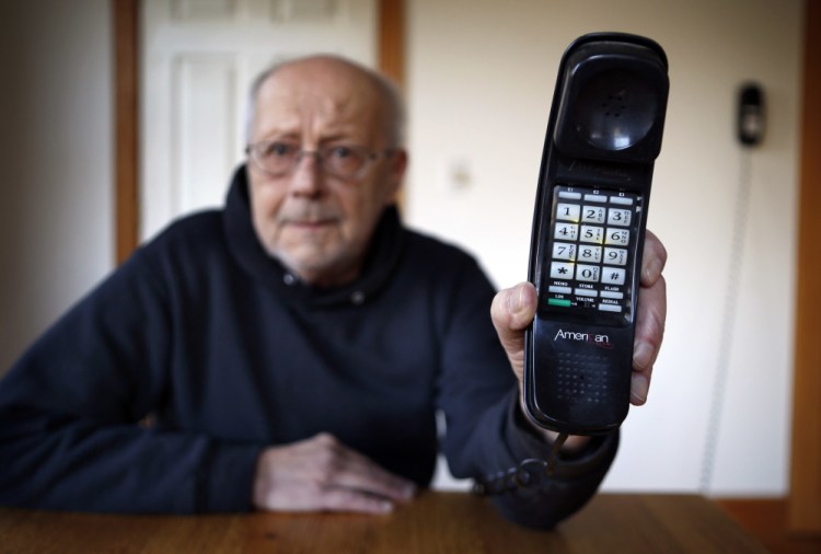 Peter Froehlich holds the landline telephone he uses at his rural home in Whitefield.. Across the country, telecom companies are lobbying lawmakers to be released from their mandate of providing service to every home.