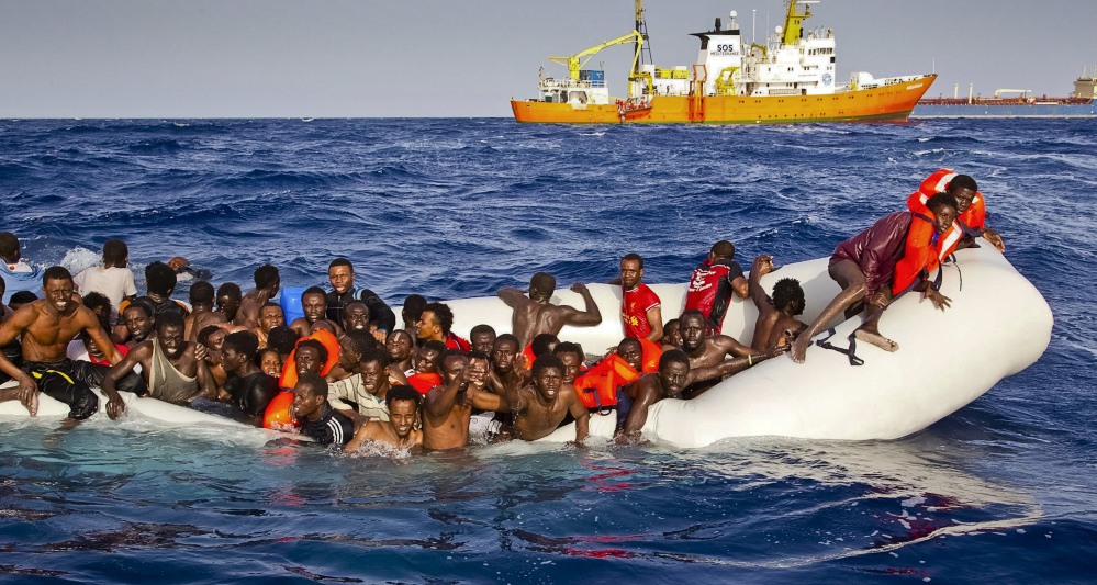 Migrants ask for help from a dinghy Sunday as they are approached by the SOS Mediterranee's ship Aquarius, background, off the coast of the Italian island of Lampedusa.