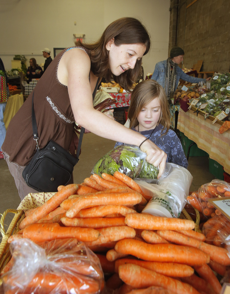  Jennifer Lehto buys carrots with her daughter Lexi Wilson-Lehto at the Portland Farmers Market on Saturday.