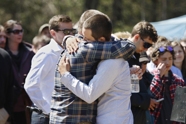 Friends of Adam Perron embrace at the memorial service. "There is no day in Adam's life we do not honor today," one friend said.
Joel Page/Staff Photographer
