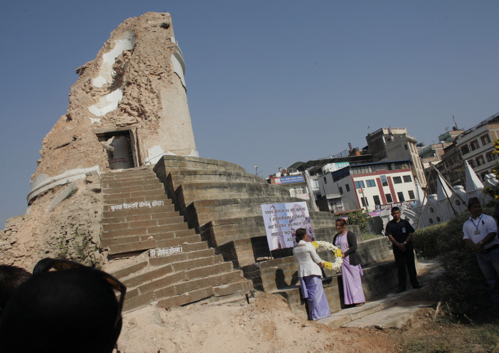 Volunteers hold a wreath as they await the arrival of Nepal's Prime Minister Khadga Prasad Oli, at the ruins of the iconic Dharahara tower in the Nepalese capital of Kathmandu on Sunday. A devastating earthquake hit Nepal one year ago.
