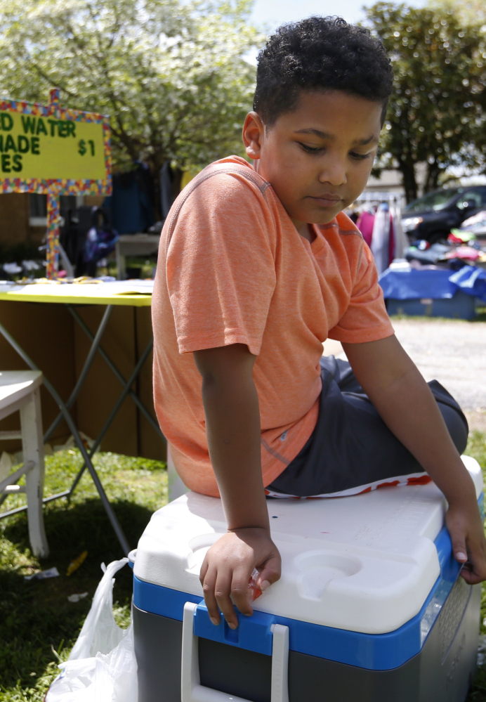 Nine-year-old Tristan Jacobson sits on a water cooler in front of his lemonade stand at his home in Springfield, Mo.