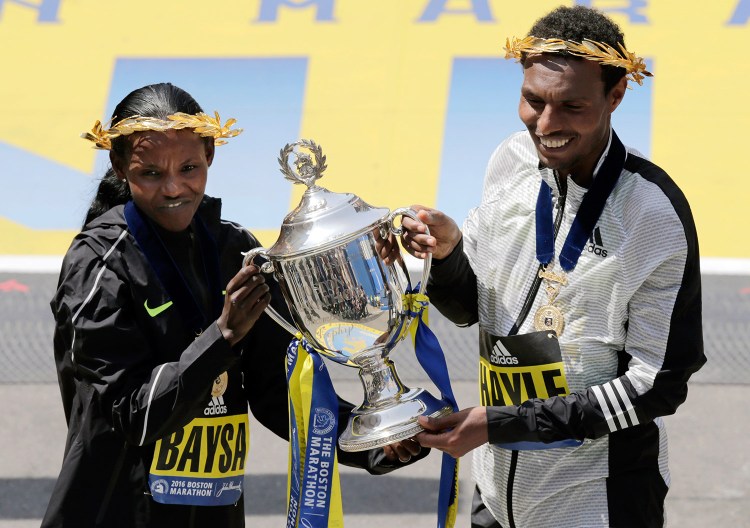 Atsede Baysa, left, and Lemi Berhanu Hayle, both of Ethiopia, hold a trophy after they won the women's and men's divisions of the 120th Boston Marathon.
