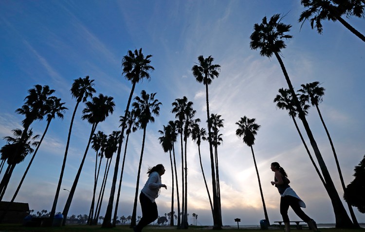 Women run as the sun sets in San Diego recently. White women have lost about five weeks from their predicted lifespan in 2014, compared to 2013, according to the CDC. The Associated Press