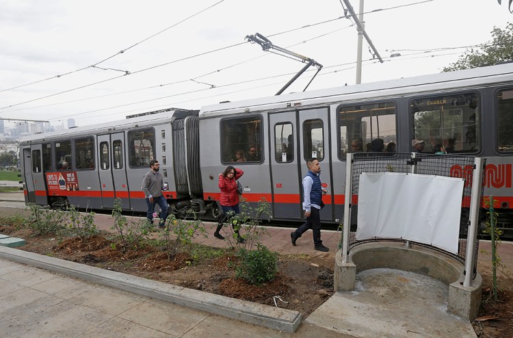 Passengers exit a San Francisco MUNI streetcar near an outdoor urinal across from Dolores Park in San Francisco. The Associated Press