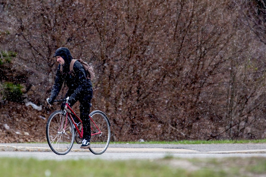 A bicyclist braces against early morning snow showers during a ride up Portland's Preble Street Tuesday, Gabe Souza/Staff Photographer