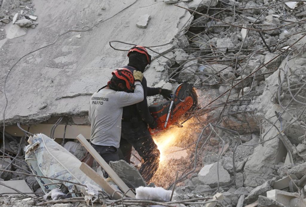 A rescue team member cuts an iron rod Tuesday at the site of a collapsed hotel in Pedernales, Ecuador. Reuters