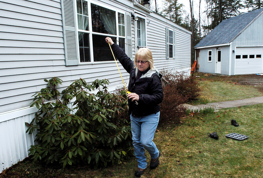 Sheryl Clifford, of Vision Government Solutions, measures a home Monday in Skowhegan for the one-year revaluation of residential and commercial properties in town.
