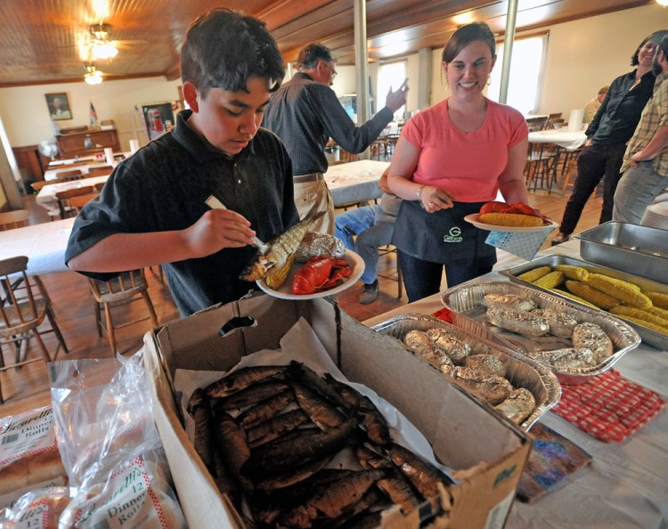 Fernando Cuares and Darcy Dow help themselves to smoked alewives and lobster in 2015 at the annual alewife festival dinner at the Benton Grange. This year's two-day Benton Alewife Festival is scheduled for May 13 and 14.