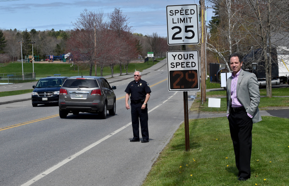 Waterville police Chief Joseph Massey, back left, and Alfond Youth Center CEO Ken Walsh, right, stand with a newly installed radar speed sign Friday across the street from the Youth Center on North Street in Waterville.