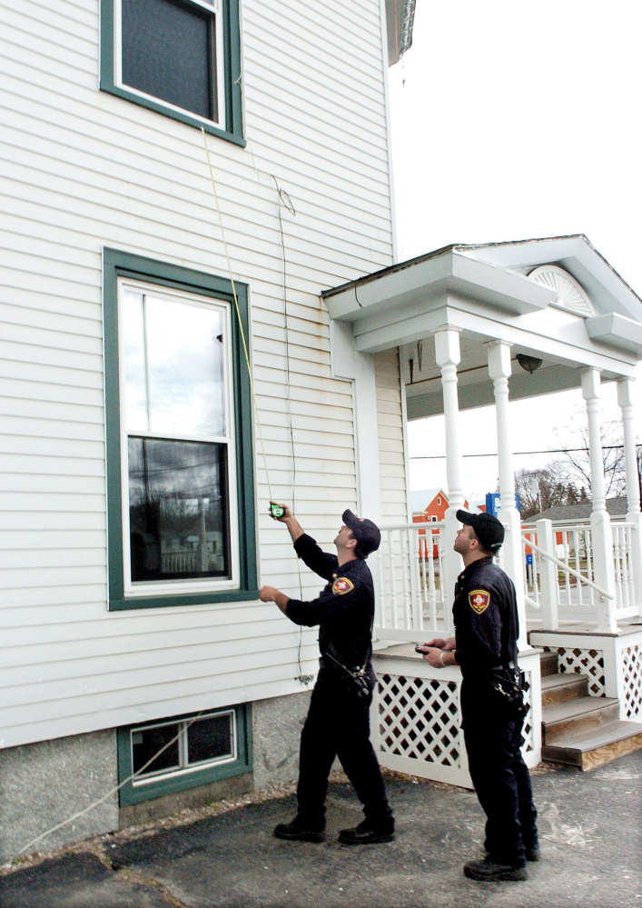Skowhegan Fire Capt. Jason Frost, left, measures the distance from a second story window to the ground as firefighter Scott Libby records the information during a safety inspection Wednesday at an apartment building in Skowhegan.