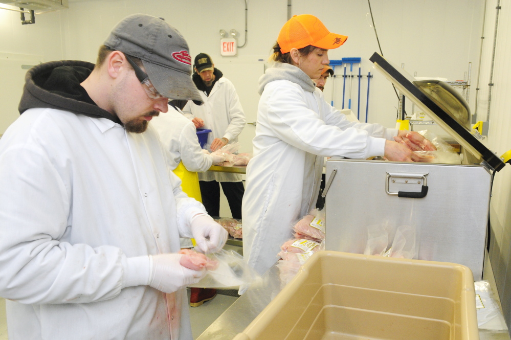 Plant manager Charlie Ripley III, left, packs chicken into bags as co-owner/manager Gina Simmons loads bags into a vacuum sealer in this March 5, 2015, file photo taken at Common Wealth Poultry Co. in Gardiner.