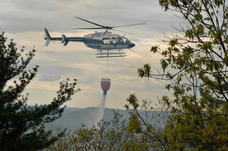 A Maine Forest Service helicopter drops water onto a forest fire Thursday afternoon on French Mountain in Rome.