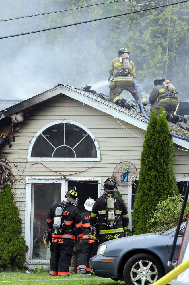 Firefighters work on the roof Saturday to put out a house fire on Pushard Lane in Gardiner.