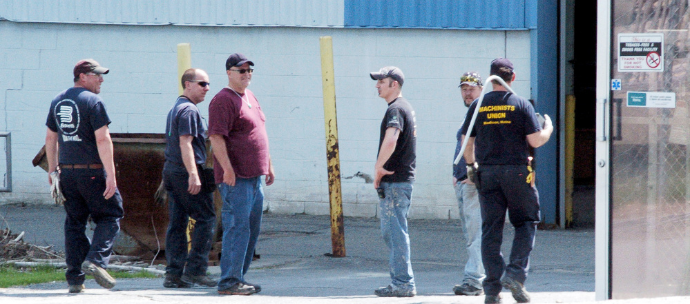 Workers congregate on the Madison Paper Industries mill property in Madison on Monday. The mill ceased production last Saturday.