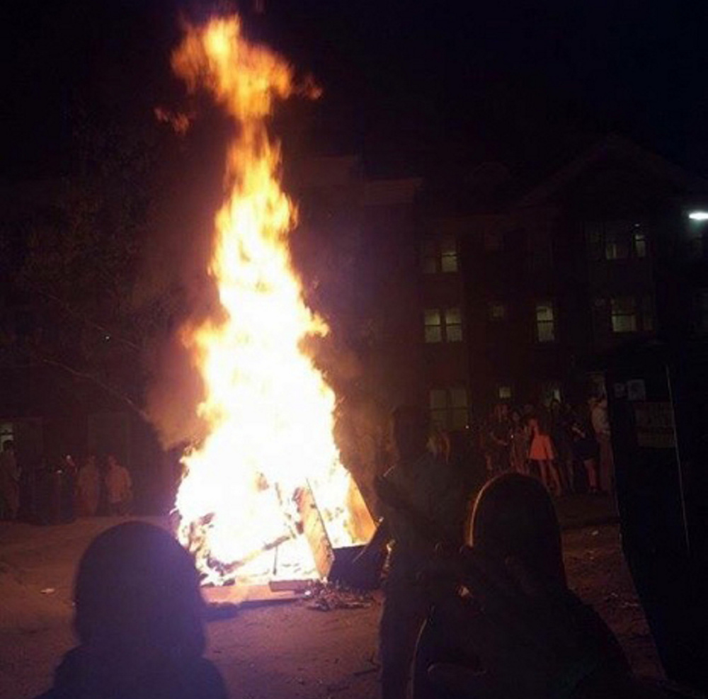 Firefighters respond to the scene of a bonfire at Colby College on Sunday. The department and Waterville police said the crowd was aggressive, and one student was arrested on charges of assault and refusing to submit to arrest.