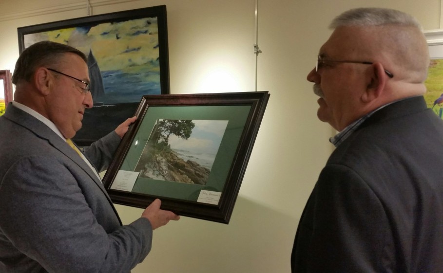 Gov. Paul LaPage accepts a photograph of the Maine coast Thursday from Alan Foley, right, the photographer, at Inland Hospital's Healing Art Gallery. LePage visited the Waterville hospital's gallery, which is displaying art by veterans until Tuesday.