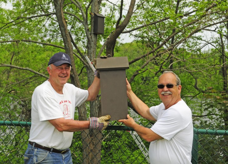City Councilor Pat Paradis, left, poses with Ray Fecteau and a bat house Friday at the Mill Park pétanque courts in Augusta. Fecteau said he hopes the bats might eat bugs attracted to the lights at the court during evening play there.