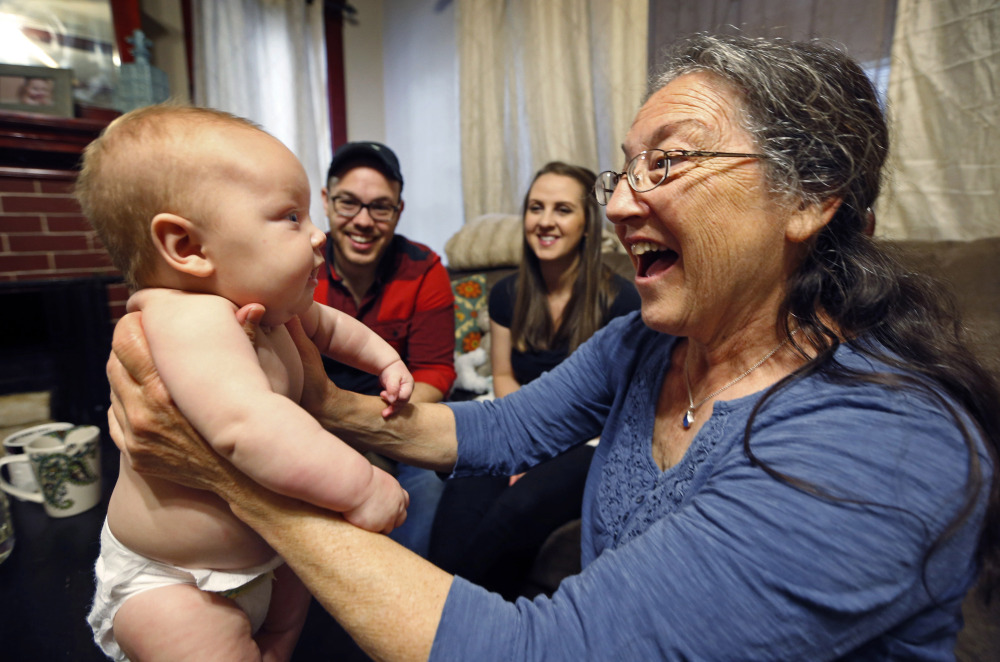 Jill Breen, a midwife, examines 10-week-old Maggie Dickson while her parents Jamie and Shannon Dickson look on at their home in Waterville. New rules will require midwives to be licensed by the state while also setting educational requirements and standards for data collection in Maine.