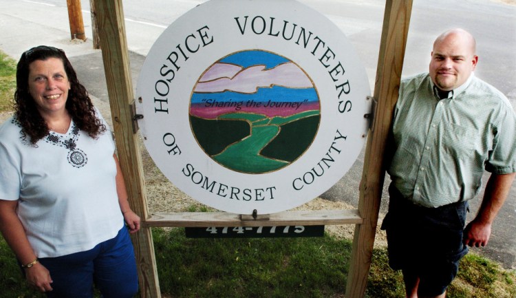 Karen Champagne, volunteer services coordinator, and Jayson Gayne, executive director of Hospice Volunteers of Somerset County, stand beside a sign at the Skowhegan facility on Wednesday. The organization is struggling financially and is seeking volunteers.