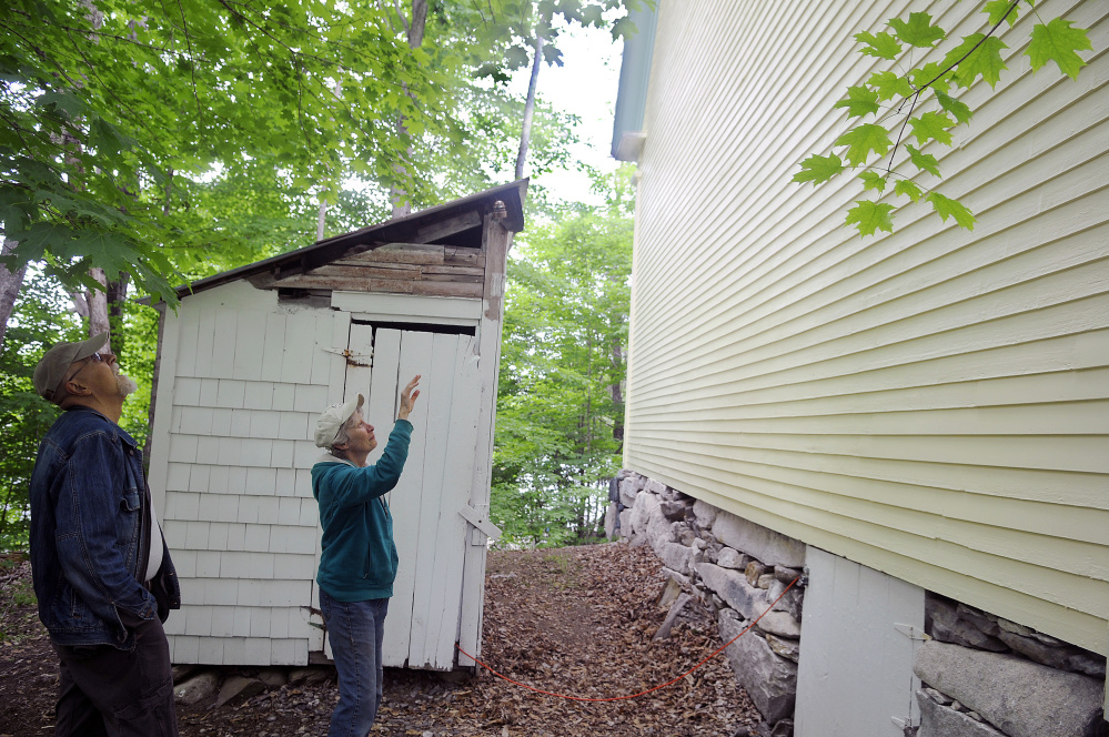 Marianne and John Archard examine the exterior paint on the rear of the Vienna Union Hall on Sunday. Renovations to the public performance space are underway, including a replacement of the outhouse at left.