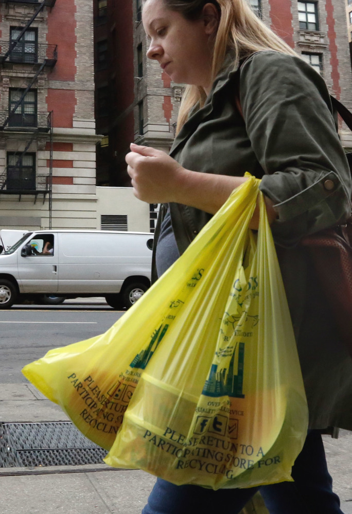 HFS BY KAREN MATTHEWS - A woman carries her purchase in plastic bags from a Gristedes supermarket on New York's Upper West Side, Thursday, May 5, 2016. Merchants in New York who now hand out billions of free, disposable plastic bags each year to shoppers and diners would have to start charging 5 cents each for the convenient but environmentally unfriendly receptacles under a bill set for a city council vote Thursday. (AP Photo/Richard Drew)