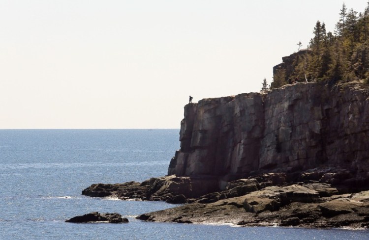 A visitor looks out over the ocean from Otter Cliffs in Acadia National Park. Numerous locals take advantage of the quiet shoulder seasons in spring and fall, when the crowds are absent from the park.