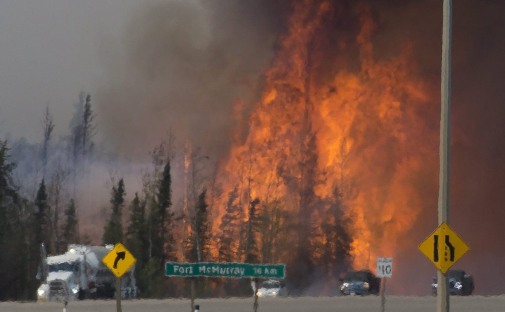 Heat waves are seen as cars and trucks try to get past a wildfire south of Fort McMurray, Alberta, on Friday.