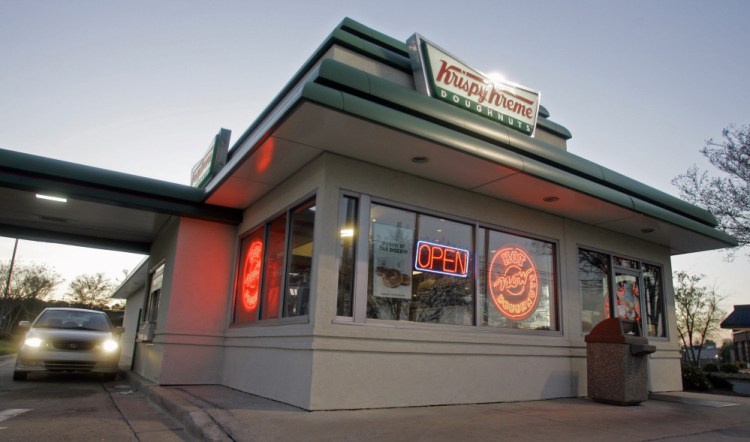 A customer picks up doughnuts at the drive through at a Krispy Kreme store in Matthews, N.C. Krispy Kreme is being taken private by JAB Beech in a deal announced Monday.