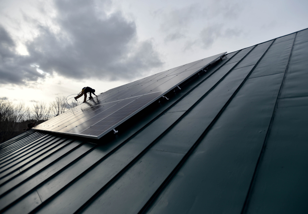 Jake Hunt, an employee with InSource Renewables in Pittsfield, installs solar panels in East Vassalboro. 