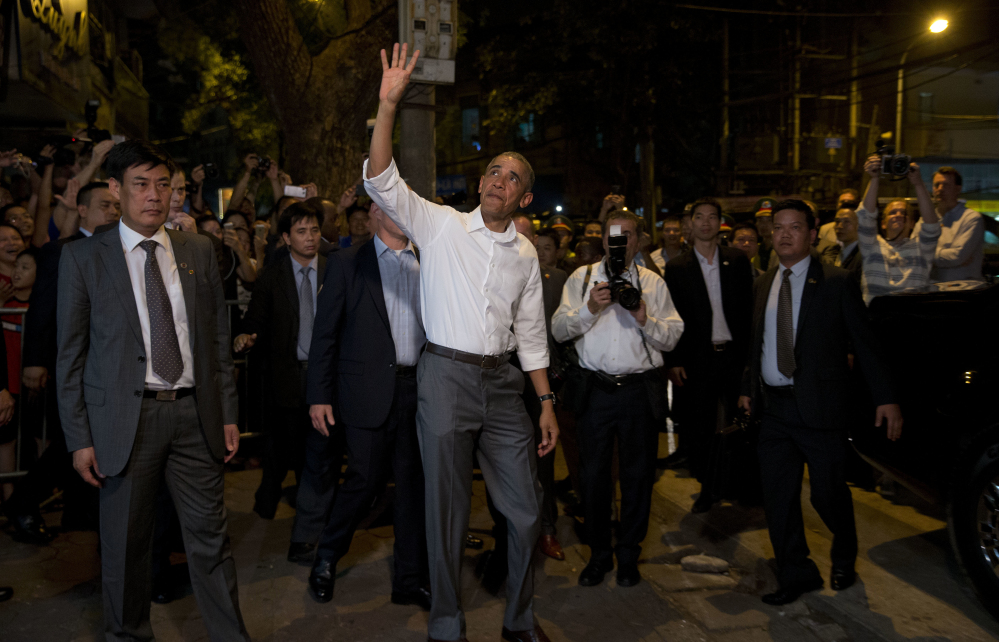 President Barack Obama waves to the gathered crowd as he walks from the Bún chả Hương Liên restaurant after having dinner with American Chef Anthony Bourdai.