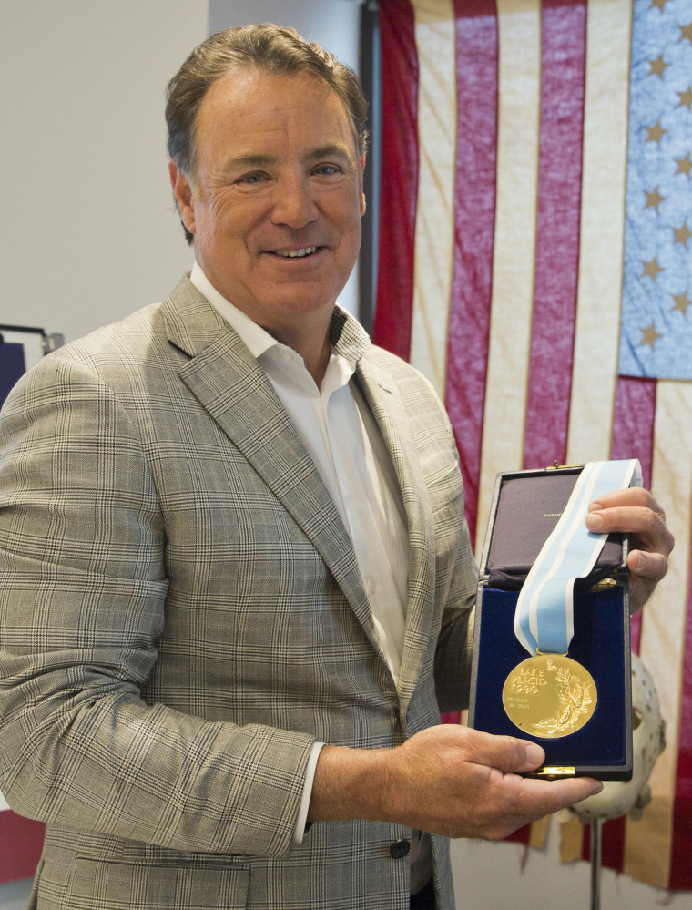 Jim Craig, the hockey goaltender who helped the U.S. win a miraculous gold medal at the 1980 winter Olympics, is framed by a display featuring the jerseys,  skates and goalie equipment he wore in the Soviet and Finland games as well as the iconic American flag that was draped over his shoulders after the gold medal win. Craig is now auctioning off the items.    The Associated Press