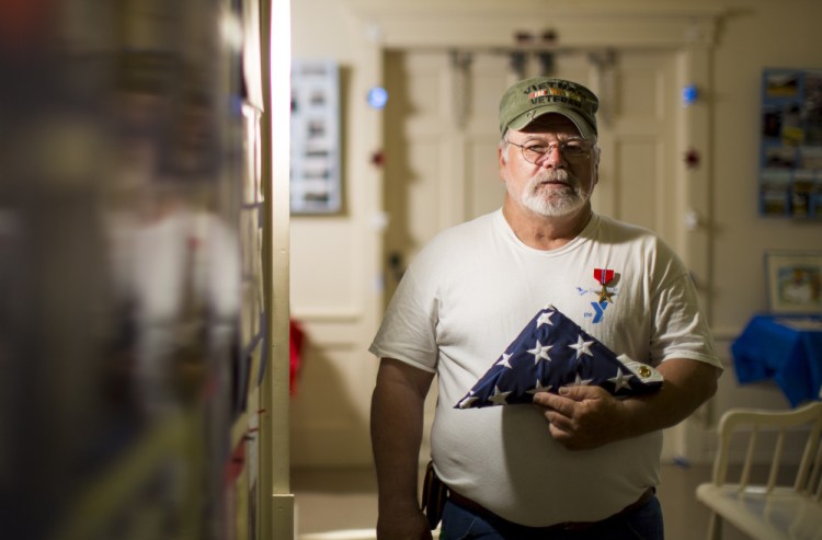 Army veteran Dennis Andrews of Boothbay Center displays a flag that flew over the White House during an event Saturday in the Southport Town Hall. Author Sarah Sherman McGrail worked with Sen. Susan Collins to honor Andrews.