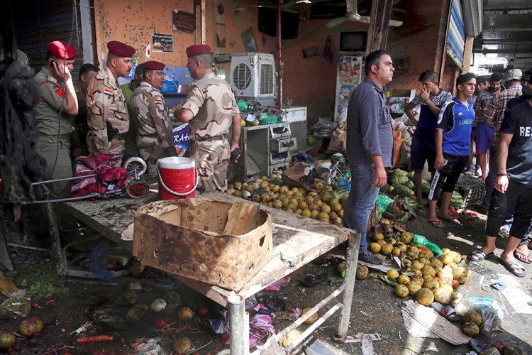 Security forces and citizens inspect the scene after a bomb exploded at an outdoor market in Baghdad's northern neighborhood of Shaab, Iraq, Tuesday. The Associated Press