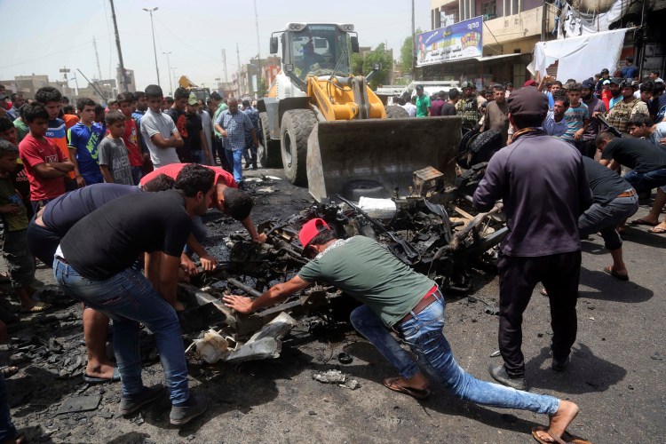 Civilians help a municipality bulldozer clean up at the scene of a car bomb explosion at a crowded outdoor market in the Iraqi capital's eastern district of Sadr City Wednesday. The Associated Press