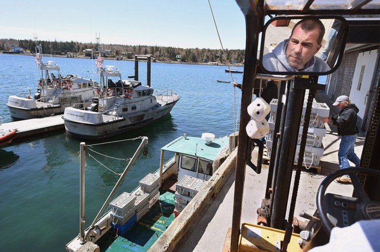 Aaron Bernstein is reflected in a mirror as he and Brian Bunker work on unloading a boat with lobsters recently from Cranberry Isles Fishermen's Co-op at Beal's Lobster Pier. They were to be picked up by Southwest Harbor's Ready Seafood  to begin their journey to China. Photo by Matt McClain/The Washington Post