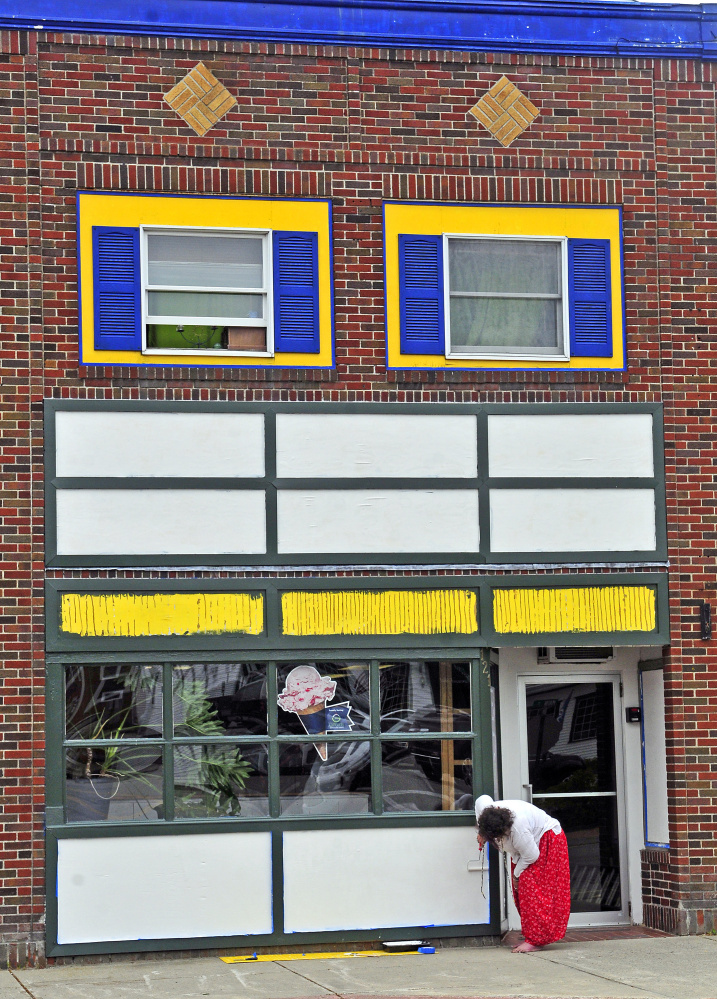 Suzi Brackin paints white over the old yellow and blue facade last week at the former Apple Valley Books that will soon be the site of Coffee & Cones on Main Street in Winthrop.