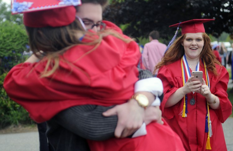 Messalonskee High School senior Julia Dudley, right, takes a photo Thursday of her classmate Alexis Bradford and her friend Dameron Rodrigue before graduation at the Augusta Civic Center.