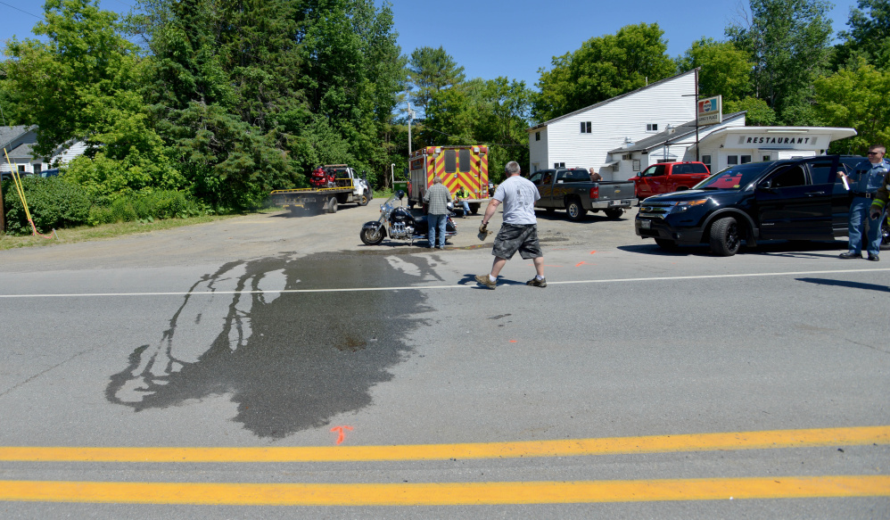 A crew clears the scene where a motorcycle and a car collided Friday morning in front of Greg's Place Restaurant on Route 3 in South China.