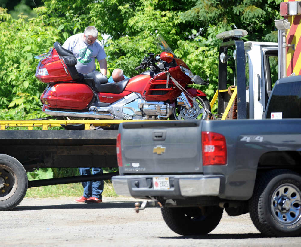 A crew loads a motorcycle that collided with a car Friday morning onto a flatbed truck later that day at Greg's Place Restaurant on Route 3 in South China.