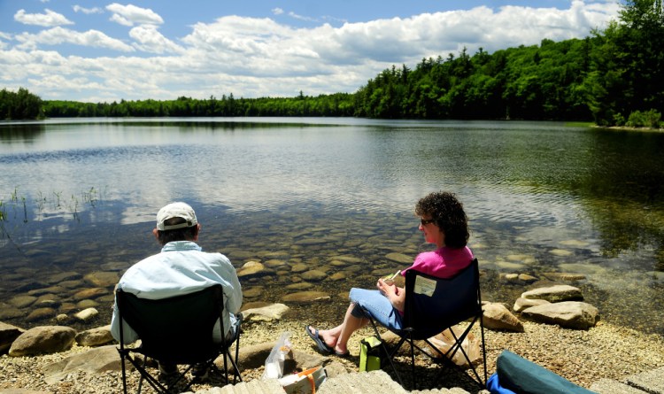 Ray Beaulieu, of Augusta, left, and his daughter Brenda Lapierre, of Poland, have an early Father's Day lunch Friday along the shore in the Jamies Pond Wildlife Management Area in Hallowell, where a timber harvest is planned to maintain wildlife habitat.