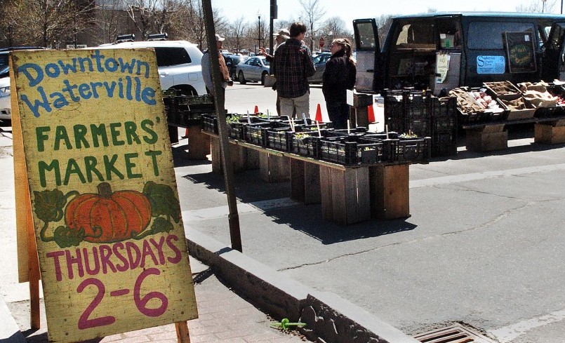 Shoppers speak with farmers from Snakeroot Organic Farm on the first day of the seasonal Downtown Waterville Farmer's Market in April. Sale of the portion of The Concourse parking lot that houses the market will account for $300,000 in revenues in the city budget.