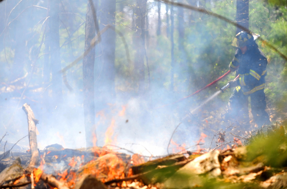 Jonathan Berringer, a firefighter with the Winslow fire department, battles a grass fire on Morrill Road in Winslow in May 2015. Fire departments across central Maine said Monday that drier than normal conditions mean a high fire danger.