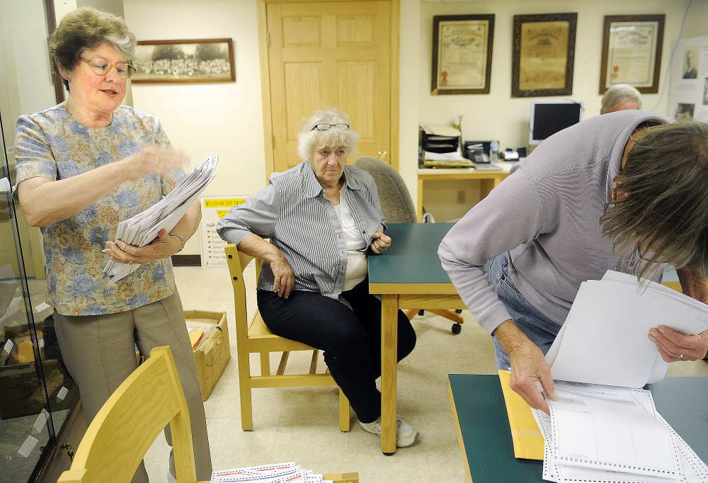 Rayna Leibowitz, left, and ballot clerk Dian White, right, inspect ballots Monday at the Litchfield town hall as Esther Slattery, seated, observes.