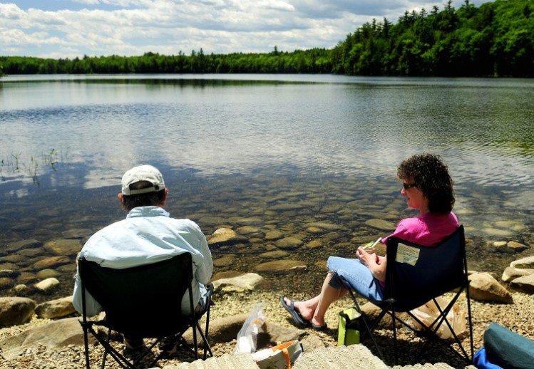 Ray Beaulieu, of Augusta, left, and his daughter Brenda Lapierre, of Poland, have an early Father's Day lunch Friday along the shore in the Jamies Pond Wildlife Management Area in Hallowell, where the state plans to implement a timber harvesting program.