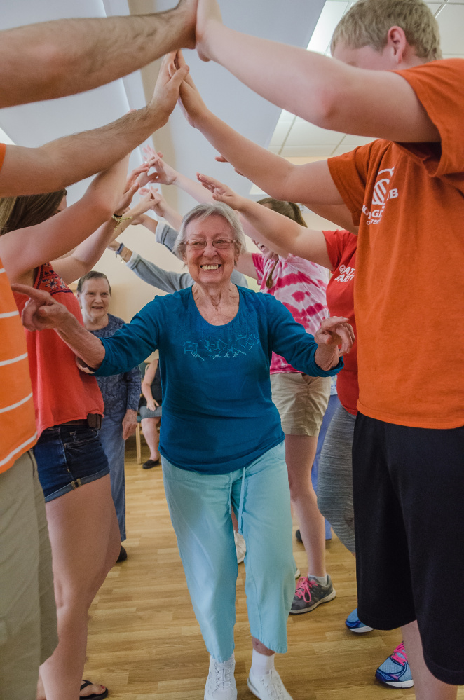Nancy Haskell of MaineGeneral's Alzheimer's Care Center in Gardiner boogies under a bridge of outstretched arms during a recent dance with the kids from the Gardiner Boys & Girls Club. This was the kids' second visit. They had come to paint flower pots and plant pansies as a community service project. They had such a fun time, they wanted to come again.