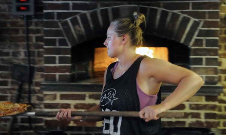 Kaylee Heath serves a pizza she baked on Aug. 17, 2015, in the brick oven at Kennebec Pizza in Hallowell. The Water Street business is scheduled to reopen soon under the new ownership of Kevin Hachey.
